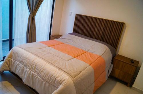 1 dormitorio con 1 cama con manta naranja y blanca en Centro Expositor, Feria de Puebla, Estadios, Acuario #1, en Puebla