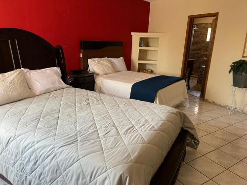 a bedroom with two beds and a red wall at Casa Huesped San Marcos in Ciudad Juárez