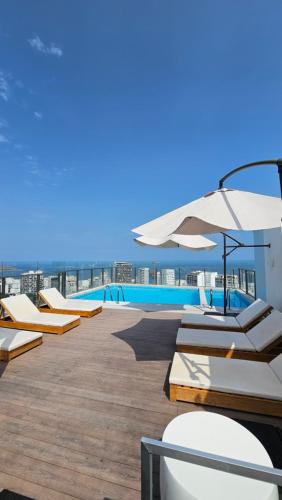 a pool with lounge chairs and an umbrella on a roof at Barranco Aparment Luxury in Lima