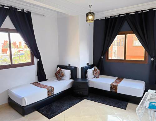 - 2 lits dans une chambre dotée de rideaux noirs dans l'établissement Residence Chay - Appartement de luxe, à Ouarzazate