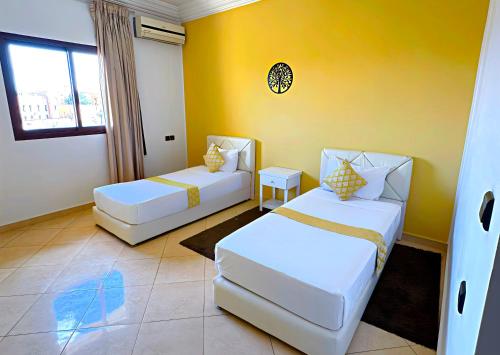 sypialnia z 2 łóżkami i żółtą ścianą w obiekcie Residence Chay - Luxury Appart w mieście Warzazat
