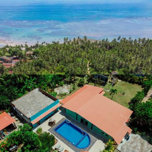 an aerial view of a house with a swimming pool and the ocean at Ajubá Pousada in Morro de São Paulo