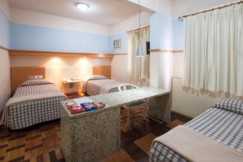 um quarto com duas camas e uma secretária em Oscar Hotel em Florianópolis