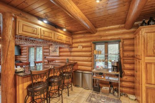 a log cabin kitchen with a bar and stools at Bear Butte Gulch Lodge in Deadwood