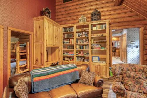a living room with a leather couch and book shelves at Bear Butte Gulch Lodge in Deadwood