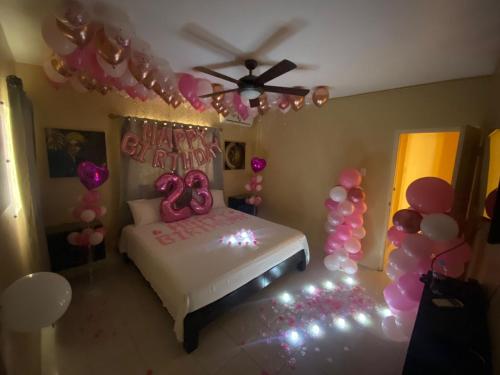 a bedroom with a bed with pink balloons and a ceiling at Marshan villa in Montego Bay