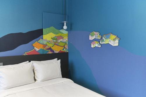 首爾的住宿－卡布奇諾酒店，卧室配有一张床,墙上挂有绘画作品