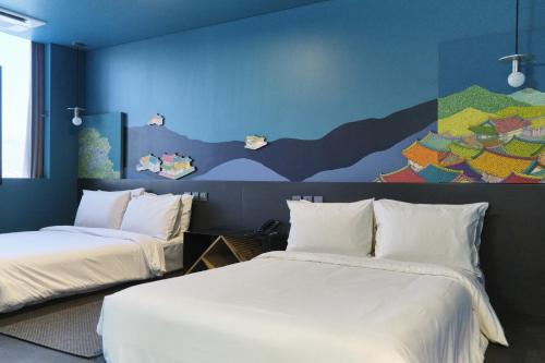 ソウルにあるホテル カプチーノの壁に絵画が飾られた部屋のベッド2台