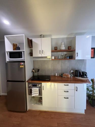 a kitchen with white cabinets and a stainless steel refrigerator at Kima Quarters in Swan Hill