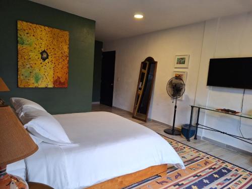 a bedroom with a white bed and a flat screen tv at Quinta Ascensión Hotel Boutique Only Adults in Malinalco