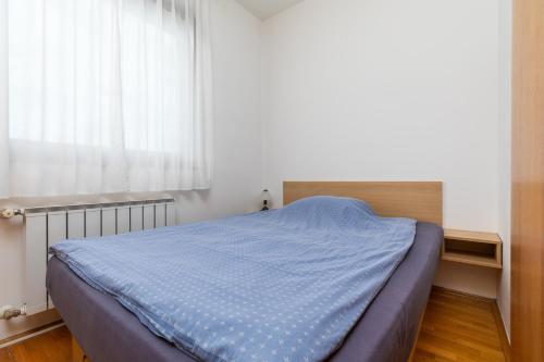 a bedroom with a bed with a blue blanket on it at Apartments with a parking space Zagreb - 22137 in Zagreb