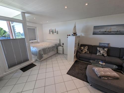 a living room with a couch and a bed at FeWo Heimathafen - Horumersiel in Wangerland