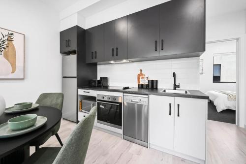 a kitchen with black and white cabinets and a table at Jolly Jubilant Jubilee in Port Adelaide