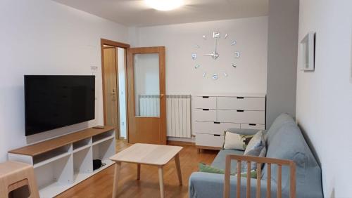 un soggiorno con un divano e un orologio a parete di Un balcon al paraiso a Cerler