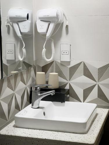 a bathroom sink with two hair dryers on a wall at Cat Ba Rose Nhung Hotel in Cat Ba
