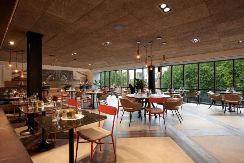 een restaurant met tafels en stoelen en grote ramen bij voco Leicester, an IHG Hotel in Leicester