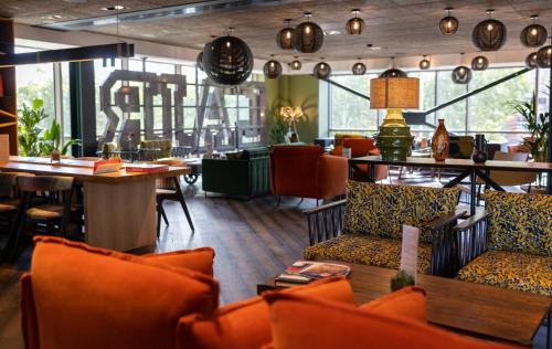 a restaurant with orange chairs and a table and a bar at voco Leicester by IHG in Leicester