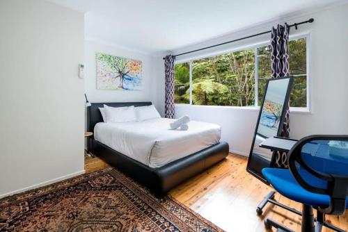 a bedroom with a bed and a desk and a window at Hope Cottage - Tamborine Mountain in Mount Tamborine