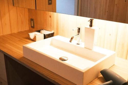 un bagno con lavandino bianco su un bancone in legno di 古民家ホテル 結 YUWAI a Hakuba