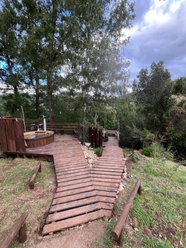 a wooden walkway in a park with a bench and trees at Wincarayen Lodge & Cabañas in Panguipulli