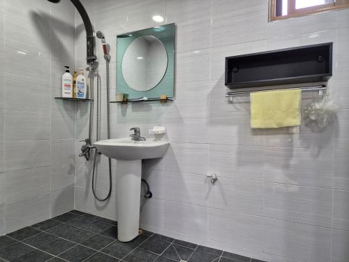 ein Bad mit einem Waschbecken und einem Spiegel in der Unterkunft Ganghwa Sweet House Pension in Incheon