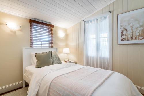 ブリスベンにあるElegant 4-Bedroom Residence with Entertaining Areaの白いベッドルーム(ベッド1台、窓付)