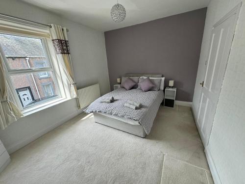 a bedroom with a bed with purple pillows and a window at Cumberland House-2 Bed House in Workington