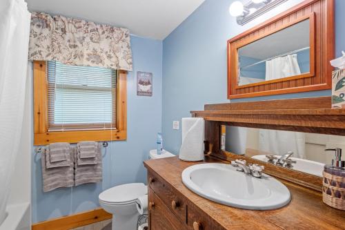 ein Badezimmer mit einem Waschbecken, einem WC und einem Spiegel in der Unterkunft Private Lakefront! - Luxury Log House! in Sanbornton