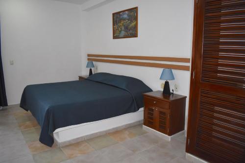 a bedroom with a blue bed and a night stand at Hotel Plaza Almendros, Isla Mujeres in Isla Mujeres