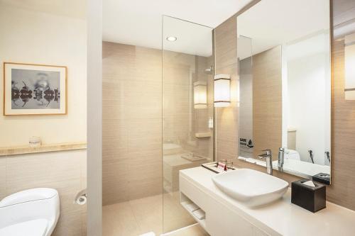 a bathroom with a sink and a toilet and a mirror at Swiss-Belhotel Jambi in Jambi