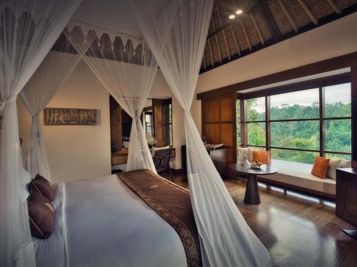 a bedroom with a bed with curtains and a couch at Hanging Gardens of Bali in Payangan