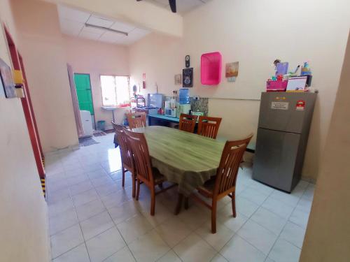 La cuisine est équipée d'une table, de chaises et d'un réfrigérateur. dans l'établissement Homestay Melewar, à Parit Raja