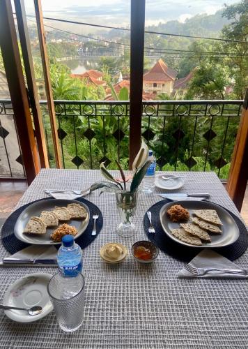 a table with plates of food on it with a view at Sesatha lake Kandy in Kandy