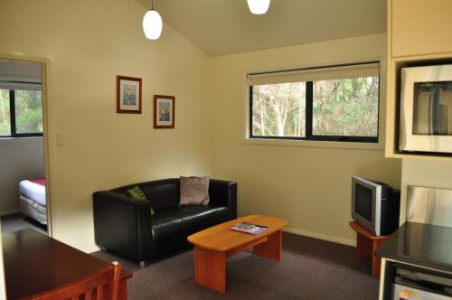 a living room with a couch and a tv at Strahan Retreat Holiday Park in Strahan