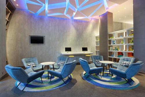 a waiting room with blue chairs and tables and a tv at Holiday Inn Express Jakarta Wahid Hasyim by IHG in Jakarta