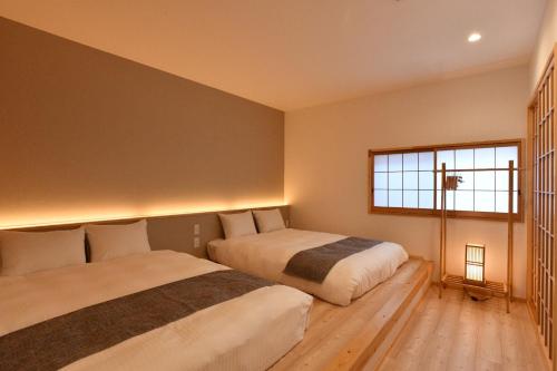 two beds in a bedroom with a window at FL House Naniwacho - Vacation STAY 13598 in Osaka