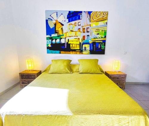 Shared Pool King Bed & Air-Conditioned Cozy Apartment في Vaïare: غرفة نوم بسرير اصفر مع لوحة على الحائط