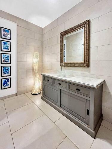 La salle de bains est pourvue d'un lavabo et d'un miroir. dans l'établissement Shared Pool King Bed & Air-Conditioned Cozy Apartment, à Vaïare