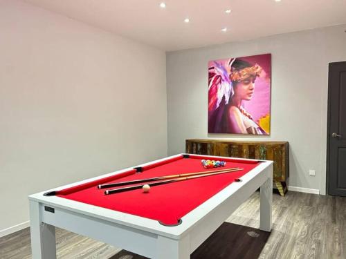 Shared Pool King Bed & Air-Conditioned Cozy Apartment في Vaïare: طاولة بلياردو حمراء في غرفة بها لوحة