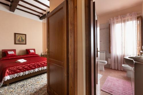 a bedroom with a red bed and a bathroom at A Casa di Franca Villa con piscina in Gambassi Terme