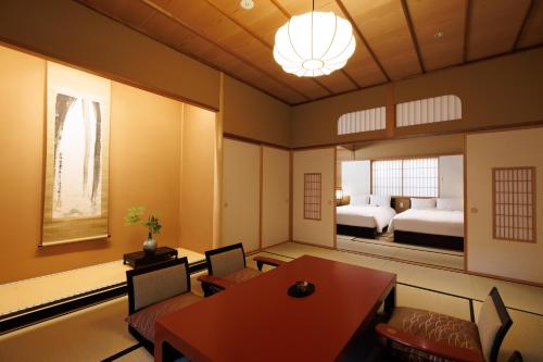 uma sala de jantar com uma mesa e um quarto em Shoraiso em Yamanouchi