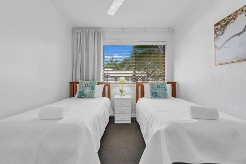 two twin beds in a room with a window at 10 Noosa Sound in Noosa Heads