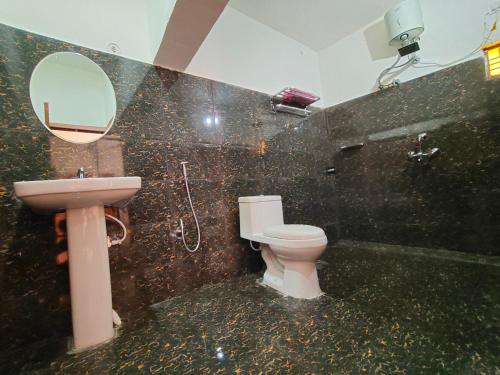 y baño con aseo, lavabo y espejo. en Alaknanda Homestay en Karnaprayāg