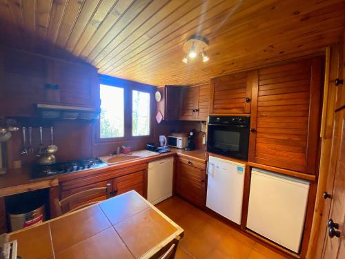 une cuisine avec des armoires en bois et un four à plaques de cuisson dans l'établissement Chalet pour 10 pers aux Angles avec poêle à granules, parking et navette - FR-1-758-26, aux Angles