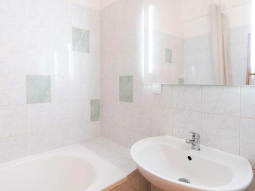 La salle de bains blanche est pourvue d'un lavabo et d'une baignoire. dans l'établissement T2 Mezzanine Climatisé Rénové - Plage des Chalets, Gruissan - 6 Pers, Parking, WiFi Option - FR-1-409-174, à Gruissan