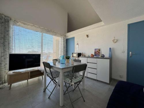 une cuisine et une salle à manger avec une table et une télévision dans l'établissement Appartement avec parking à Gruissan, 4 couchages, proche plage - FR-1-229-886, à Gruissan