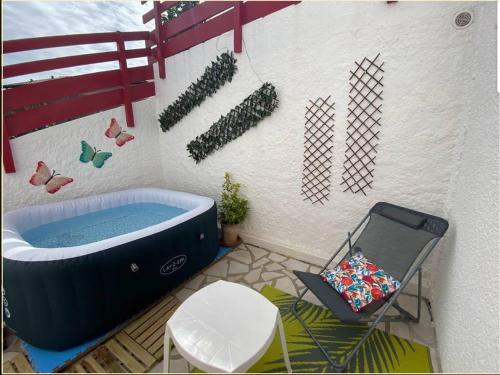une salle de bain avec une baignoire, une table et une chaise dans l'établissement T1 Bis Charmant à Bidart, 2 Pers, 900m Plage, Terrasse et Spa, Quartier Calme - FR-1-495-137, à Bidart