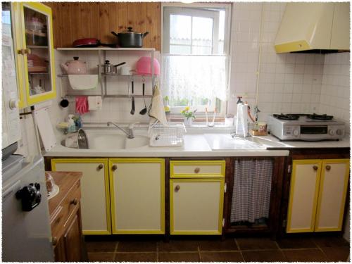 eine Küche mit gelben Schränken und einem Waschbecken in der Unterkunft Folks House in Eniwa