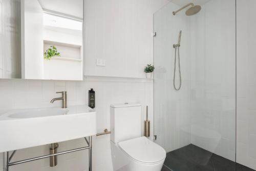een witte badkamer met een toilet en een wastafel bij Urban Rest Double Bay Apartments in Sydney