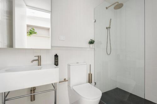 a white bathroom with a toilet and a sink at Urban Rest Double Bay Apartments in Sydney